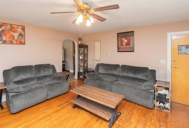 living room featuring a ceiling fan, arched walkways, and wood finished floors