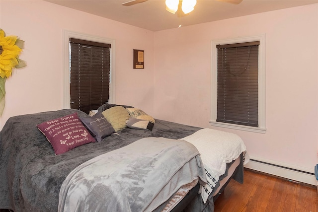 bedroom with ceiling fan, a baseboard radiator, and wood finished floors