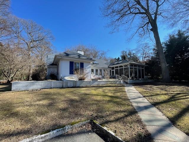 view of front facade featuring a front yard and a sunroom