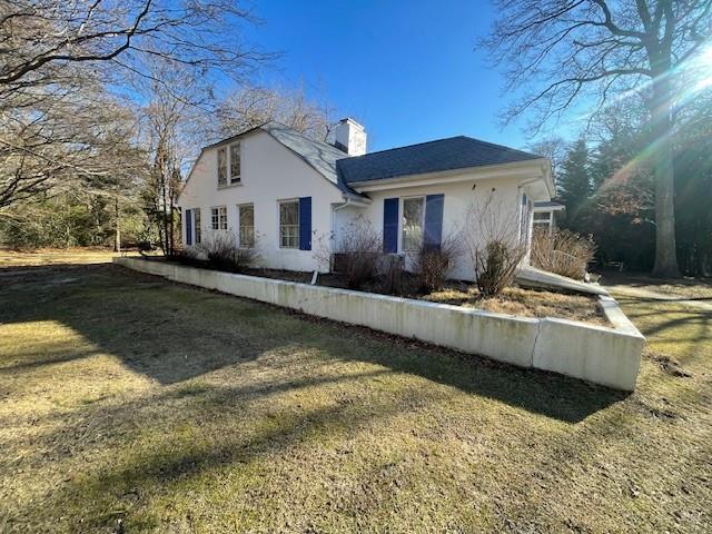 view of side of property with a chimney, a lawn, and stucco siding