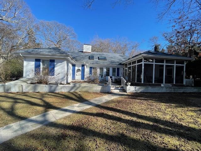 view of front facade featuring a sunroom and a chimney