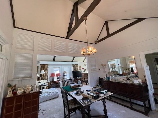 dining area featuring high vaulted ceiling, french doors, concrete flooring, and an inviting chandelier