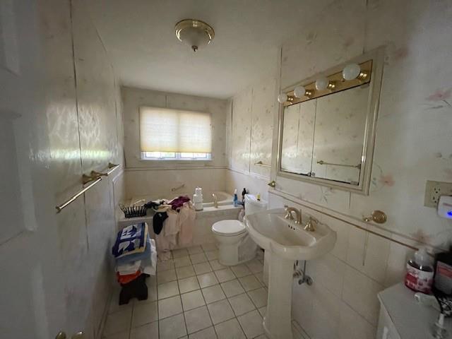 bathroom featuring toilet, a bath, and tile patterned floors