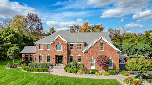 colonial inspired home featuring brick siding and a front lawn