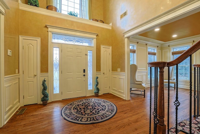 entrance foyer with wood finished floors, visible vents, and a decorative wall