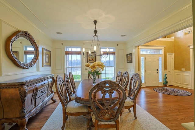 dining area featuring a notable chandelier, ornamental molding, dark wood-type flooring, and a decorative wall