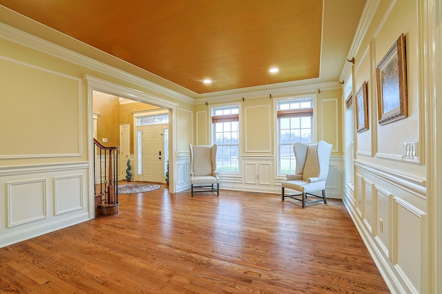 unfurnished room with crown molding, wood finished floors, and a decorative wall