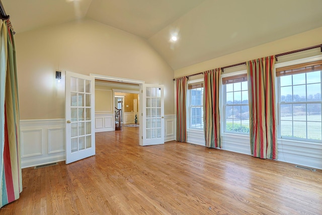 unfurnished room with light wood finished floors, french doors, a wainscoted wall, and visible vents