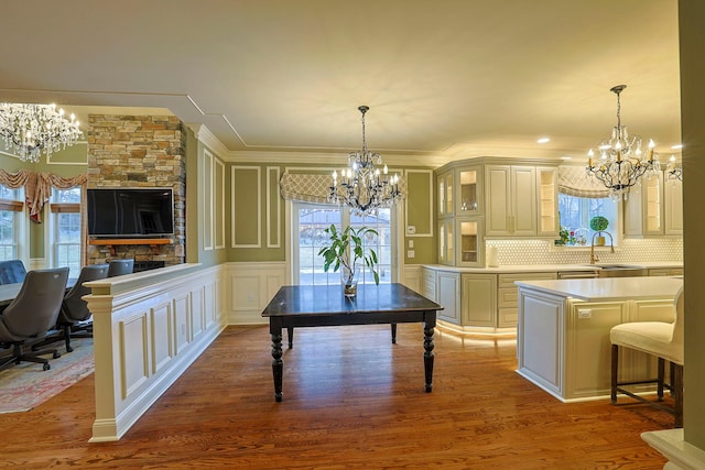 kitchen featuring decorative backsplash, wood finished floors, light countertops, a chandelier, and a decorative wall