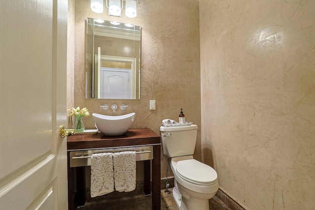 bathroom featuring a textured wall, vanity, and toilet