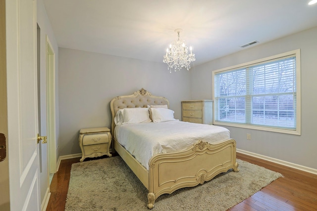 bedroom with dark wood-style floors, visible vents, baseboards, and an inviting chandelier