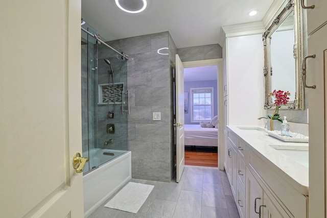 ensuite bathroom with double vanity, bath / shower combo with glass door, ensuite bath, tile patterned flooring, and a sink