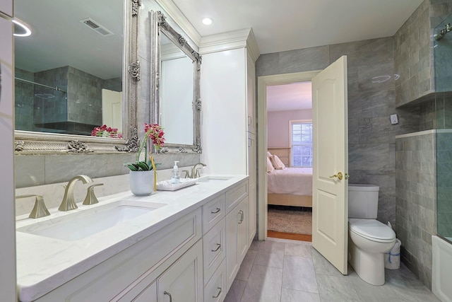 ensuite bathroom featuring toilet, tiled shower, a sink, and visible vents