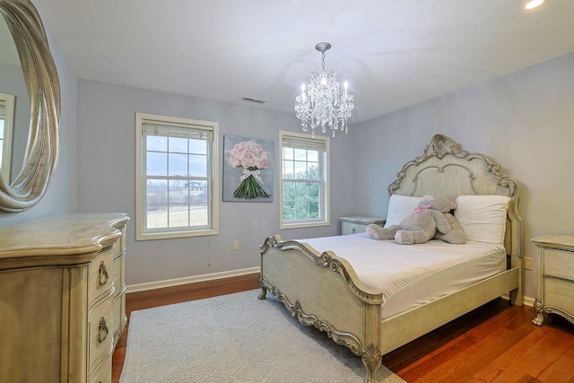 bedroom featuring dark wood-type flooring, a chandelier, visible vents, and baseboards