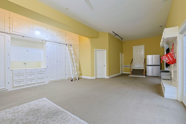 interior space featuring light carpet, baseboards, and stairs