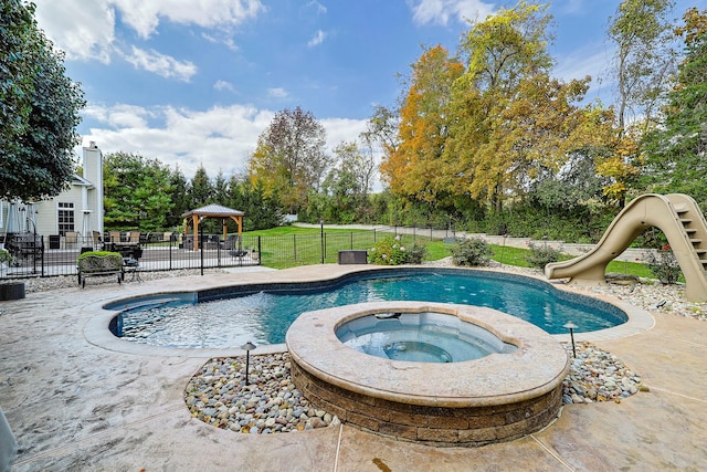 view of pool featuring a patio, a water slide, an in ground hot tub, fence, and a fenced in pool