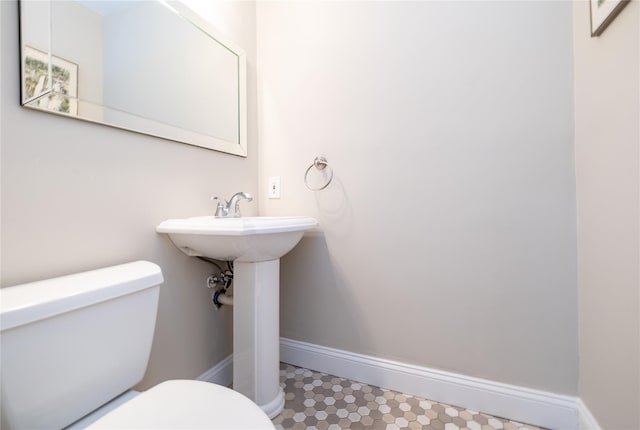 half bathroom featuring tile patterned floors, toilet, and baseboards