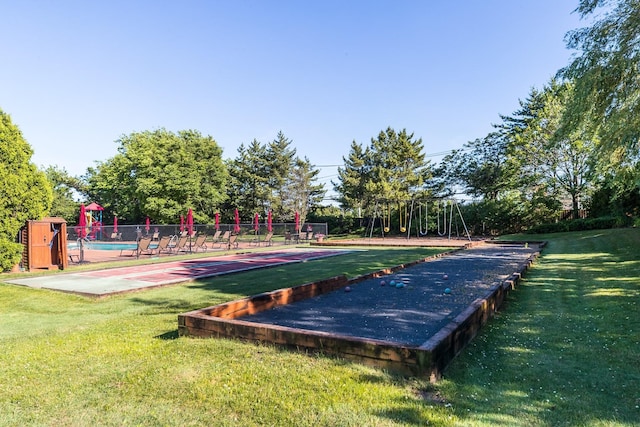 view of property's community featuring playground community, a yard, and fence