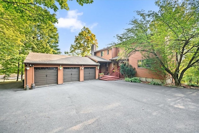 exterior space with driveway, an attached garage, and a chimney