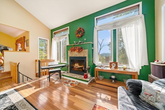 sitting room with a wealth of natural light, vaulted ceiling, an upstairs landing, and wood finished floors