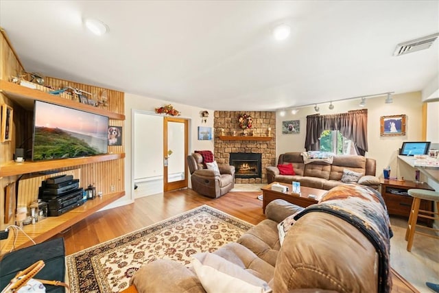 living room featuring rail lighting, a fireplace, visible vents, and wood finished floors