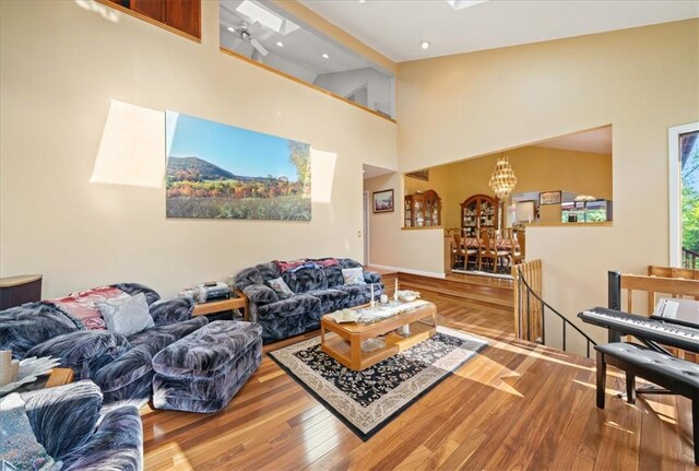 living room with a high ceiling, wood finished floors, and an inviting chandelier