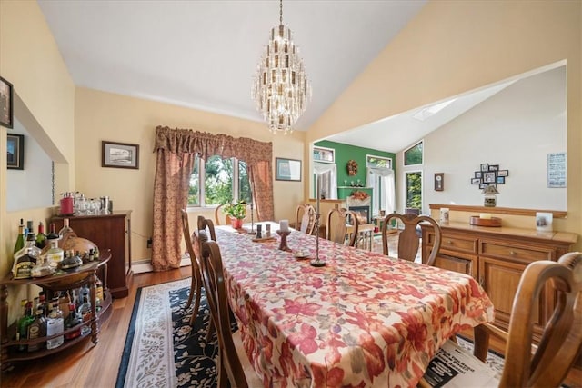 dining space featuring vaulted ceiling, wood finished floors, and a notable chandelier