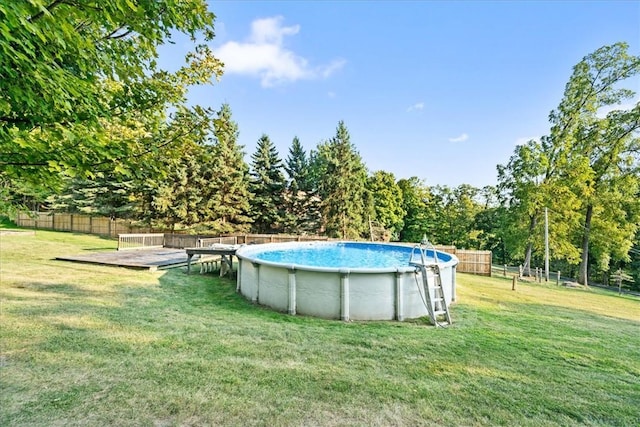 outdoor pool featuring fence and a yard