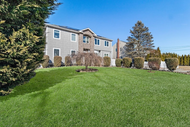 view of front of property featuring solar panels and a front yard