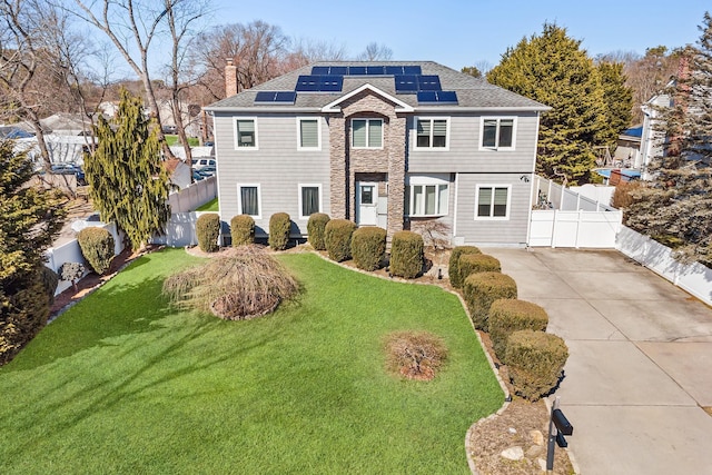 view of front of home featuring a fenced backyard, a chimney, a front lawn, and solar panels