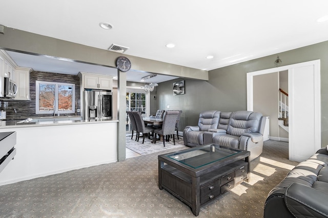 living area featuring recessed lighting, visible vents, light carpet, baseboards, and stairs