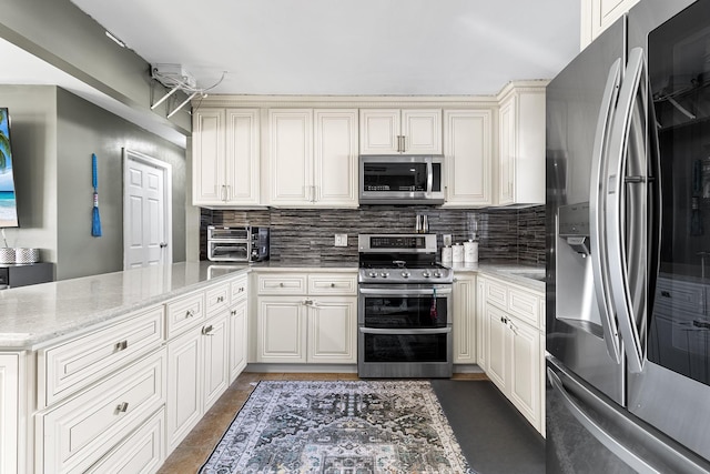 kitchen featuring tasteful backsplash, a toaster, a peninsula, light stone countertops, and stainless steel appliances