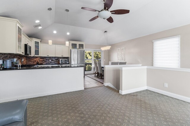 kitchen with vaulted ceiling, stainless steel appliances, dark countertops, and backsplash