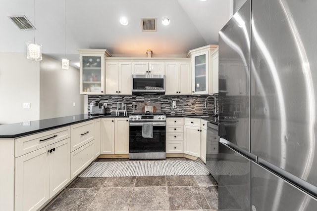 kitchen with a peninsula, visible vents, stainless steel appliances, and decorative backsplash