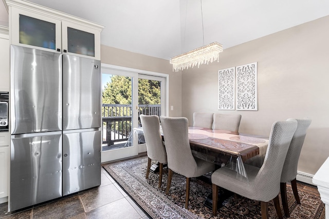 dining room with lofted ceiling, a baseboard radiator, and a notable chandelier