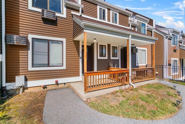 view of property with a wall mounted air conditioner and a porch