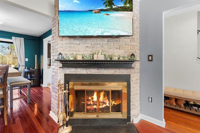 details featuring a glass covered fireplace, wood finished floors, and baseboards
