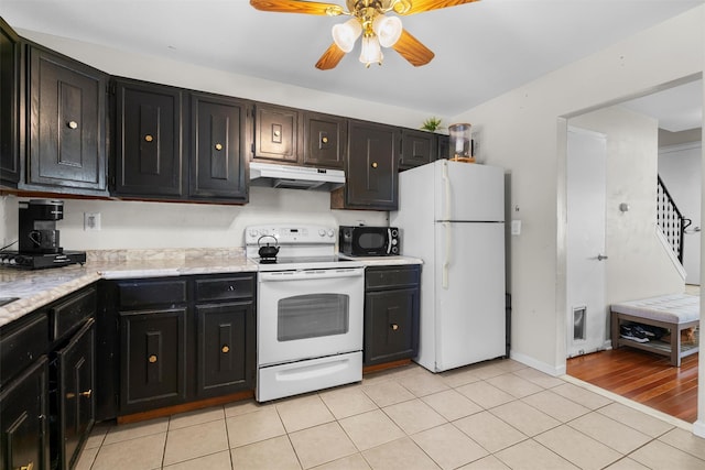 kitchen with under cabinet range hood, light tile patterned floors, dark cabinetry, white appliances, and a ceiling fan