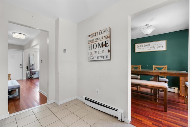 hallway with light tile patterned flooring, a baseboard heating unit, and baseboards