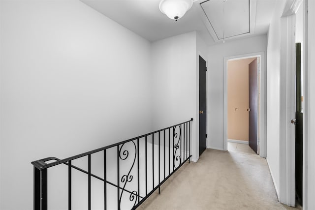 corridor with attic access, an upstairs landing, baseboards, and light carpet