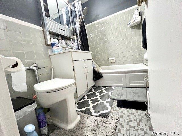 full bath featuring toilet and tile walls