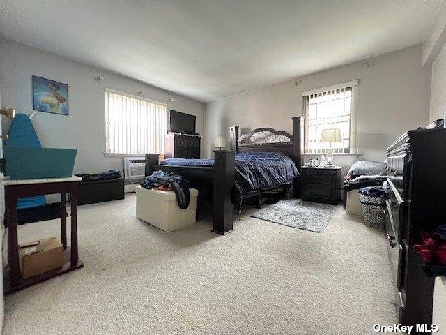 bedroom featuring carpet, an AC wall unit, and multiple windows