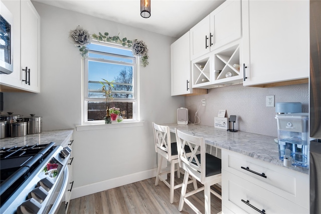 kitchen with appliances with stainless steel finishes, white cabinets, baseboards, and light stone countertops