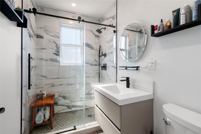 bathroom featuring toilet, a marble finish shower, and vanity