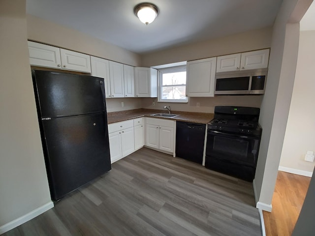 kitchen featuring black appliances, wood finished floors, and white cabinetry