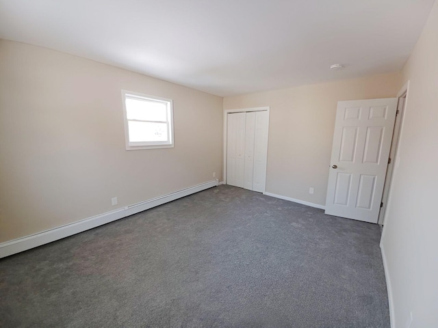 unfurnished bedroom featuring a baseboard heating unit, dark colored carpet, a closet, and baseboards