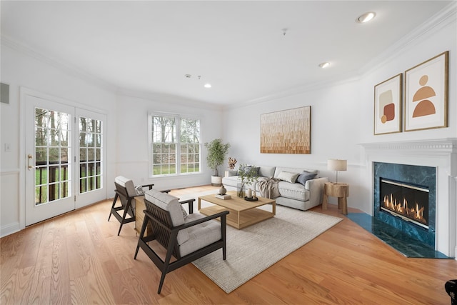 living area with recessed lighting, a high end fireplace, light wood-type flooring, and ornamental molding
