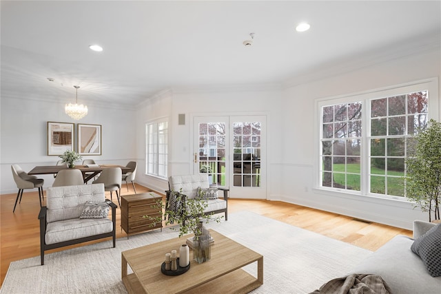 living room with a chandelier, crown molding, and light wood-style floors