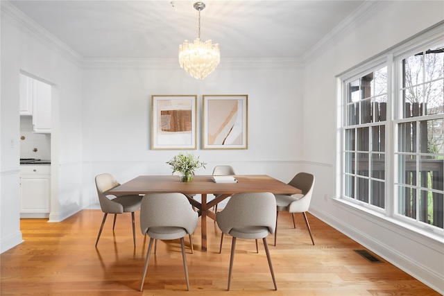 dining area with light wood-style flooring, a healthy amount of sunlight, a notable chandelier, and visible vents