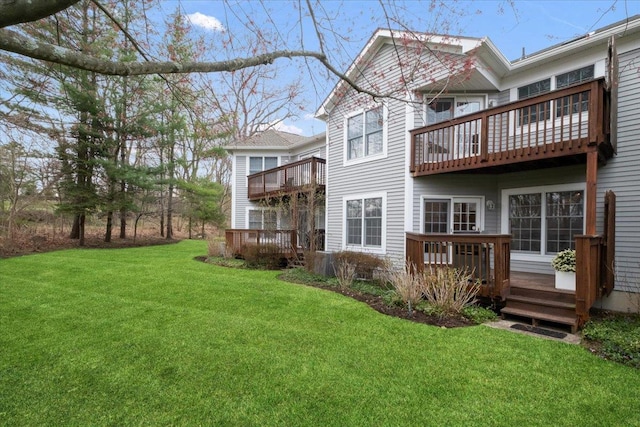 rear view of house featuring a wooden deck, a lawn, and a balcony